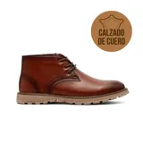 Bota casual tipo chukka de cuero color marrón, con cordones al tono, costuras reforzadas y suela de goma dentada en color beige.