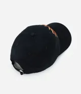 Gorra de sarga de algodón color negro con visera curva y ajuste trasero regulable. Presenta un bordado frontal con lettering en tonos tierra.