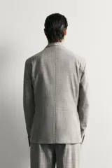 Blazer regular fit de Zara, confeccionada en tejido con mezcla de lana y algodón con diseño de cuadros grises. Cuenta con solapas de pico, doble botonadura cruzada, bolsillos con solapa en la cadera y bolsillo de vivo en el pecho.