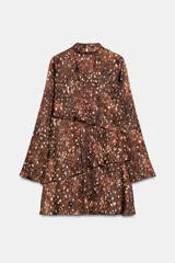 Vestido corto de cuello redondo y manga larga, con diseño de volantes superpuestos en el frente. Presenta un estampado abstracto en tonos marrones y cierre en la espalda con abertura y botones.