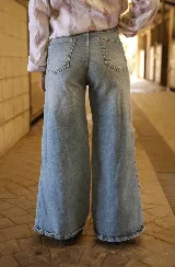 Jean de corte recto y tiro alto, confeccionado en denim de tono azul claro con acabado lavado. Presenta cierre frontal con botón metálico y bolsillos laterales.