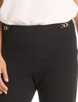 Pantalón sastrero de corte recto confeccionado en crepé negro, de diseño pull-on con apliques metálicos dorados en los laterales de la cintura. Cuenta con bolsillos laterales simulados y pinzas traseras de entalle.
