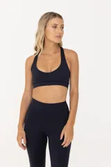 Top deportivo de sujeción media, confeccionado en poliamida y elastano. Presenta un diseño con escote redondo, breteles finos y banda elástica en la cintura para mayor ajuste y soporte. Cuenta con doble tela interna para mayor seguridad durante el entrenamiento.