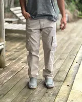 Pantalón cargo de corte holgado, color arena, confeccionado en gabardina elastizada. Presenta bolsillos laterales con solapa en los muslos, costuras reforzadas en las rodillas y cierre frontal con botón y cremallera.