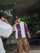 Chomba de piqué con diseño color block vertical en negro y verde oscuro, cuello polo y cierre frontal parcial. Presenta inscripciones en el frente.