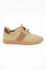 Zapatilla de gamuza en tono verde pistacho con detalles en cuero marrón, cordones al tono con cuentas decorativas y suela de goma color caramelo.