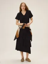 Vestido midi de morley color negro, de manga corta, escote en V y falda con volados asimétricos en capas.