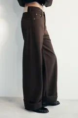 Jeans de tiro medio con corte baggy y pierna relajada. Presenta diseño de cinco bolsillos, cierre frontal con cremallera y botón, y bajo acabado con vuelta.