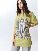 Remera negra de manga corta, corte oversize, con estampado frontal de una figura femenina de estilo asiático rodeada de flores blancas y verdes.