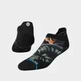 Medias tobilleras negras con tecnología FEEL360™ y refuerzo Infiknit™. Presentan un estampado tropical en la zona del empeine con hojas verdes y una flor de ave del paraíso naranja. Tienen un borde azul claro con texto en la punta.