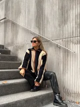 Campera de corderito con diseño de rayas verticales en colores beige y negro, con cierre frontal y detalles de ribete en color marrón.