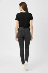 Pantalón jean de mujer, color negro lavado, tiro medio y calce ajustado (skinny). Presenta cinco bolsillos y cierre frontal con botón.