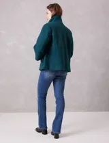 Tapado de tejido bouclé color marrón, con silueta evasé y largo a la cadera. Presenta cuello alto envolvente, cierre frontal oculto con botones a presión y bolsillos frontales de gran tamaño. Sus mangas son 3/4 con corte amplio y puños de tejido rib al tono que se extienden para cubrir las muñecas.