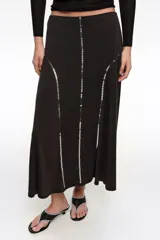 Falda midi de corte línea A, color negro, decorada con líneas verticales de lentejuelas brillantes.