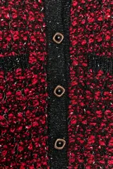 Chaqueta de punto con textura y estructura de tweed, en combinación de rojo y negro. Cuenta con cuello redondo, manga larga, bolsillos delanteros de plastrón y cierre frontal con botones metálicos dorados.