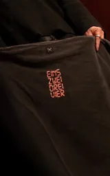Remera de manga corta con cuello redondo y calce oversize, color negro con efecto lavado. Presenta un estampado frontal gráfico con motivos musicales y tipografía en tonos rojos y blancos.