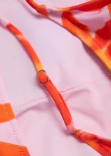 Malla enteriza con estampado floral en tonos naranja sobre fondo claro, de escote redondo y tirantes finos ajustables con espalda abierta.