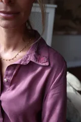 Camisa de fibrana color violeta con cuello clásico y detalle de bordado floral en una de las puntas del cuello.