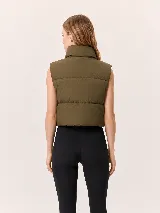 Chaleco puffer de corte cropped y diseño acolchado, con cuello alto y cierre frontal completo. Presenta un acabado liso en color marrón oscuro.