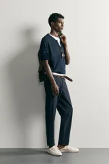 Pantalón chino negro slim fit de corte recto, con bolsillos frontales, trabillas para cinturón y cierre frontal con cremallera y botón.