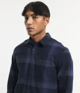 Camisa de manga larga con diseño de cuadros en tonos marrones, confeccionada en algodón. Presenta cuello camisero, cierre frontal con botones y un bolsillo en el pecho con botón.
