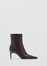 Botin de cuero caprino color marrón oscuro, con diseño de punta fina y tacón kitten de 6,5 cm. Cuenta con cierre de cremallera lateral.