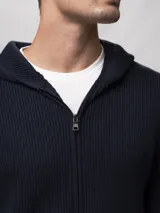 Campera tejida con capucha, confeccionada en poliéster, con cierre frontal completo y diseño de punto acanalado.