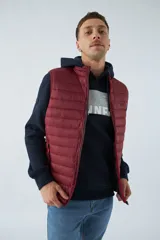 Chaleco puffer verde oliva con cierre frontal y bolsillos laterales con cierre. Interior forrado en color naranja.