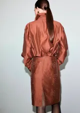 Camisa de manga larga de tejido mezcla lyocell en color marrón cobrizo, con cuello camisero, cierre frontal de botones ocultos y aplicación de strass brillante disperso por toda la prenda.