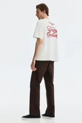 Remera boxy de algodón color blanco, con cuello redondo acanalado, mangas cortas y hombros caídos. Presenta un pequeño estampado rojo en el pecho con las inscripciones 'ROWING CLUB W1F'.