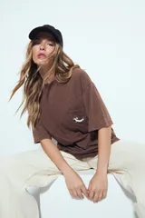 Remerón de manga corta color marrón con efecto "washed/dye" que le da un aspecto gastado. Tiene un bolsillo aplicado en el pecho con un bordado de perro salchicha.