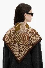 Pañuelo cuadrado con diseño de patchwork que combina diversos estampados animales como leopardo, cebra y jirafa en tonos marrones y beige, con bordes en color marrón oscuro.