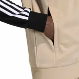 Campera deportiva Adidas Originals SST de corte ajustado, con diseño combinado en color tostado en el cuerpo y negro en las mangas. Cuenta con escote bomber, cierre frontal completo y las clásicas tres tiras blancas a lo largo de las mangas. Incluye el logo del trifolio bordado en el pecho.