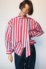 Camisa de manga larga con cuello subido y detalle de lazada frontal. Presenta un diseño de rayas verticales en tonos verde y celeste, con cierre frontal de botones y puños clásicos.