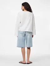 Blusa blanca de algodón con escote en V y mangas largas abullonadas. Presenta cierre frontal con lazos.