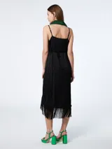 Vestido corto negro con breteles finos, escote en V, corte irregular con flecos y un bolsillo lateral.