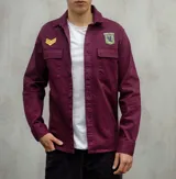 Sobrecamisa bordeaux de gabardina con cuello clásico, cierre frontal abotonado, dos bolsillos con solapa abotonada en el pecho y apliques bordados en el pecho y el hombro. Corte recto y mangas largas con puños abotonados.