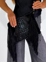 Bandolera negra con textura símil piel de cocodrilo, con flecos de gamuza en los laterales y correa de cadena dorada.