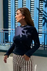 Remera de manga larga color azul marino, con cuello redondo y puños decorados con volados sutiles.