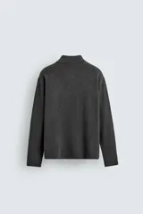 Polo de punto de manga larga con cuello solapa y cierre frontal de botones. Presenta un diseño de corte regular con aberturas laterales en el bajo.