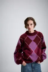 Jersey de punto de lana con diseño de rombos en tonos bordó y lila. Presenta cuello redondo, manga larga con puños ajustados y corte holgado.