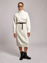 Vestido midi de punto con cuello alto tipo poleron, de corte holgado y mangas largas con puños acanalados. Presenta un diseño en color blanco con sutiles motas de colores.