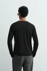 Camiseta negra de corte relaxed fit, confeccionada en tejido ligero con algodón. Presenta cuello redondo y manga ranglán larga.