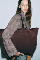 Bolso tipo maxi shopper de serraje marrón, con doble asa de hombro y costura central vertical.