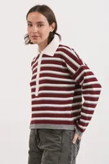 Sweater de tejido bremer con diseño de rayas horizontales en tonos vino, gris y blanco. Presenta cuello polo con solapa abotonada, mangas largas y corte holgado.