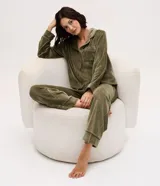 Pijama de dos piezas estilo americano confeccionado en plush. La parte superior es una camisa de manga larga con cuello solapa, cierre frontal abotonado y bolsillo en el pecho. El pantalón cuenta con cintura elástica con cordón ajustable y ruedos plegados.