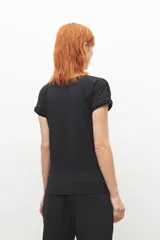 Remera negra de corte recto, con cuello en V y detalle de trenzas en los hombros.