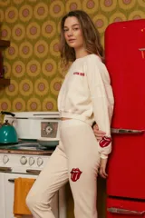 Pantalón de jogging color crema con logo de los Rolling Stones en rojo en la pierna.