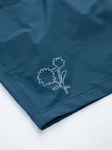 Short de baño color lila con cintura elástica y cordón ajustable. Tiene un pequeño bordado de una flor en la pierna izquierda y un parche con el logo de la marca en la pierna derecha.