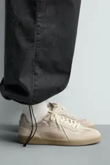 Zapatilla de estilo retro con cordones y efecto desgastado, confeccionada en una combinación de materiales con detalles de piel con acabado serraje y suela de goma a contraste.